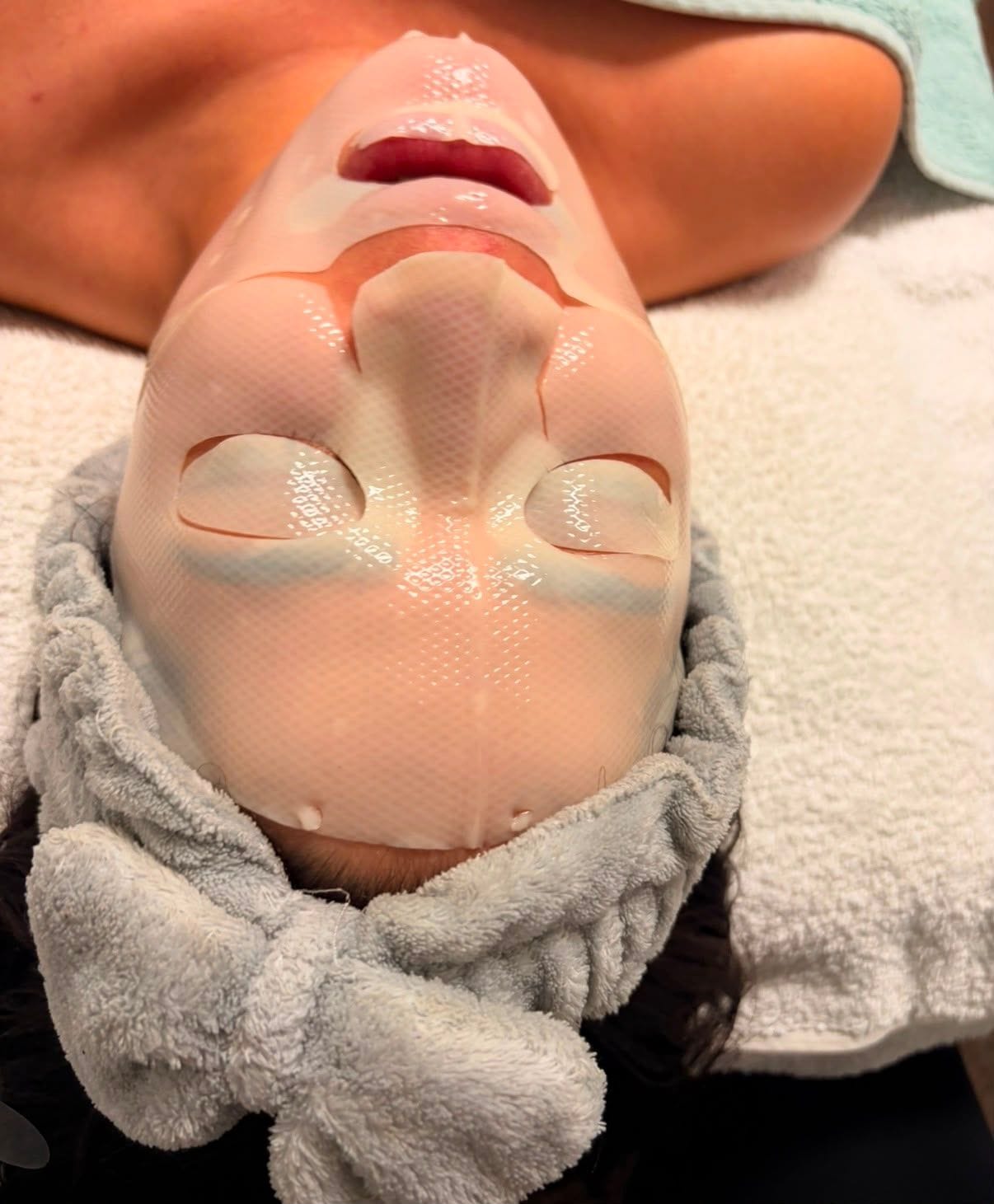 A hydrating collagen sheet mask smoothed over a client's face to finish a facial.